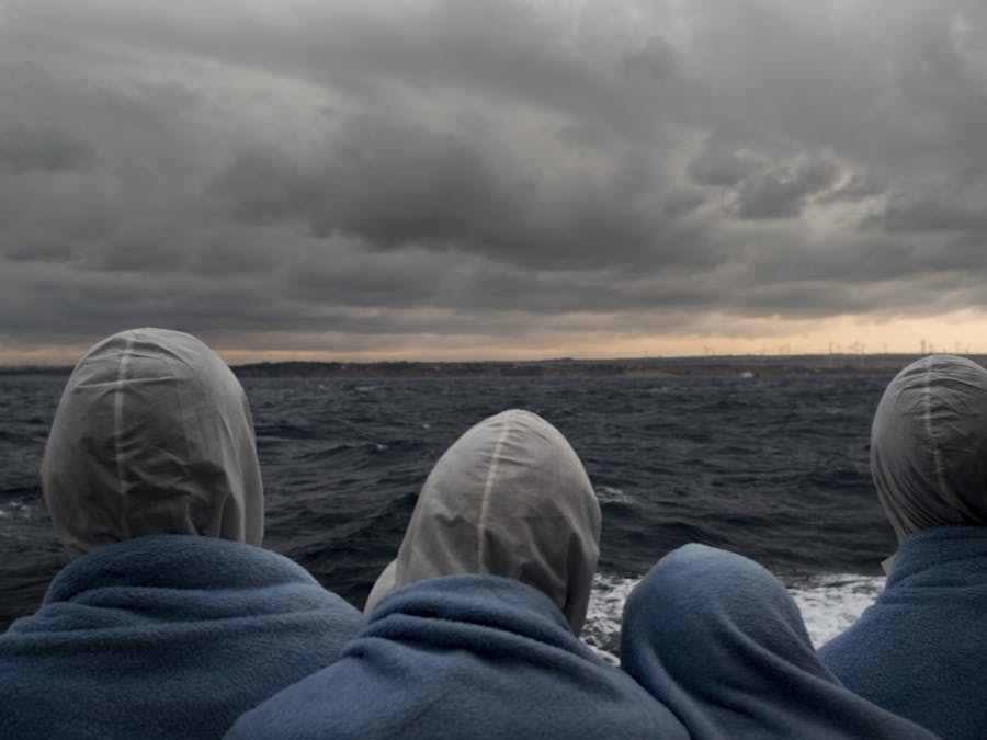Migranten kijken naar de kust van Italië nadat ze zijn gered in de SAR zone.