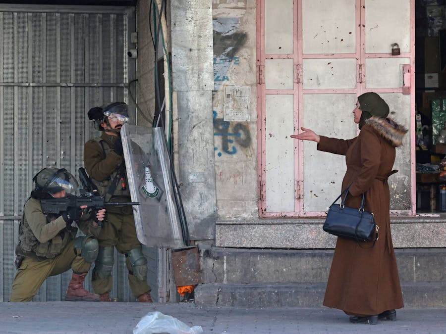 vrouw maakt een gebaar naar de Israëlische veiligheidstroepen die rubberkogels afvuren om Palestijnse stenengooiers uit elkaar te drijven tijdens botsingen in de stad Hebron op de Westelijke Jordaanoever.