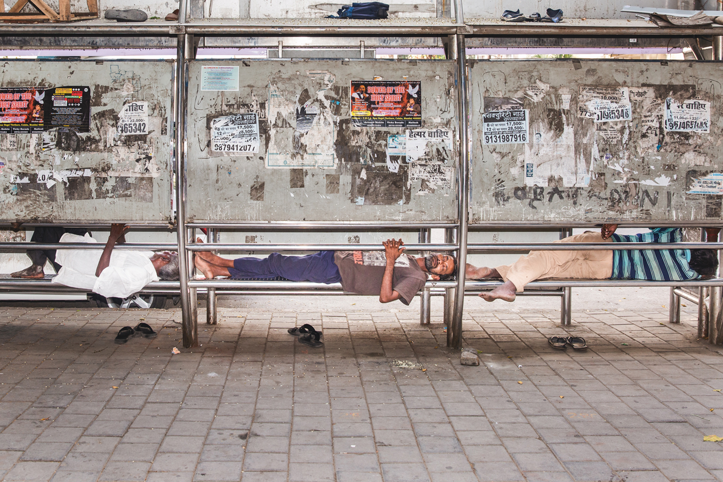 61% Humidity, 30°C. Three men sleep on the bench of a bus stop in Churchgate, a wealthy neighborhood of Mumbai. India, 2019 - foto voor Wordt Vervolgd van The cooling solution