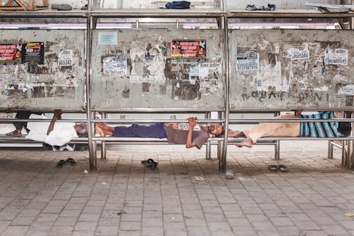 61% Humidity, 30°C. Three men sleep on the bench of a bus stop in Churchgate, a wealthy neighborhood of Mumbai. India, 2019 - foto voor Wordt Vervolgd van The cooling solution