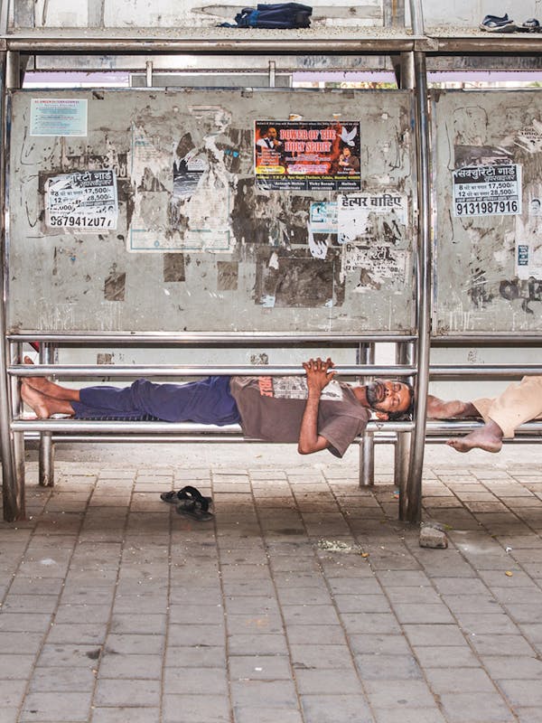 61% Humidity, 30°C. Three men sleep on the bench of a bus stop in Churchgate, a wealthy neighborhood of Mumbai. India, 2019 - foto voor Wordt Vervolgd van The cooling solution