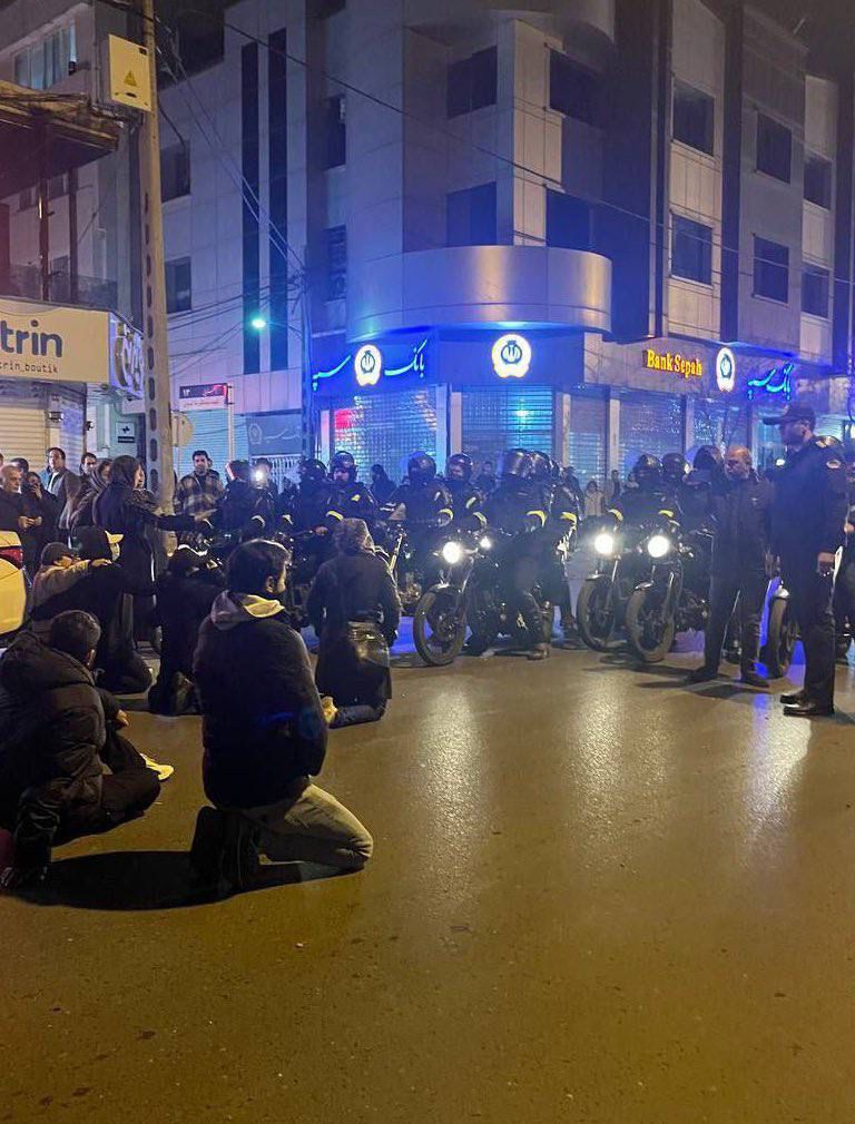 Demonstranten houden op 3 januari 2026 een vreedzame sit-in in Mashhad. Voor hen, op de motoren, zitten leden van de veiligheidstroepen.