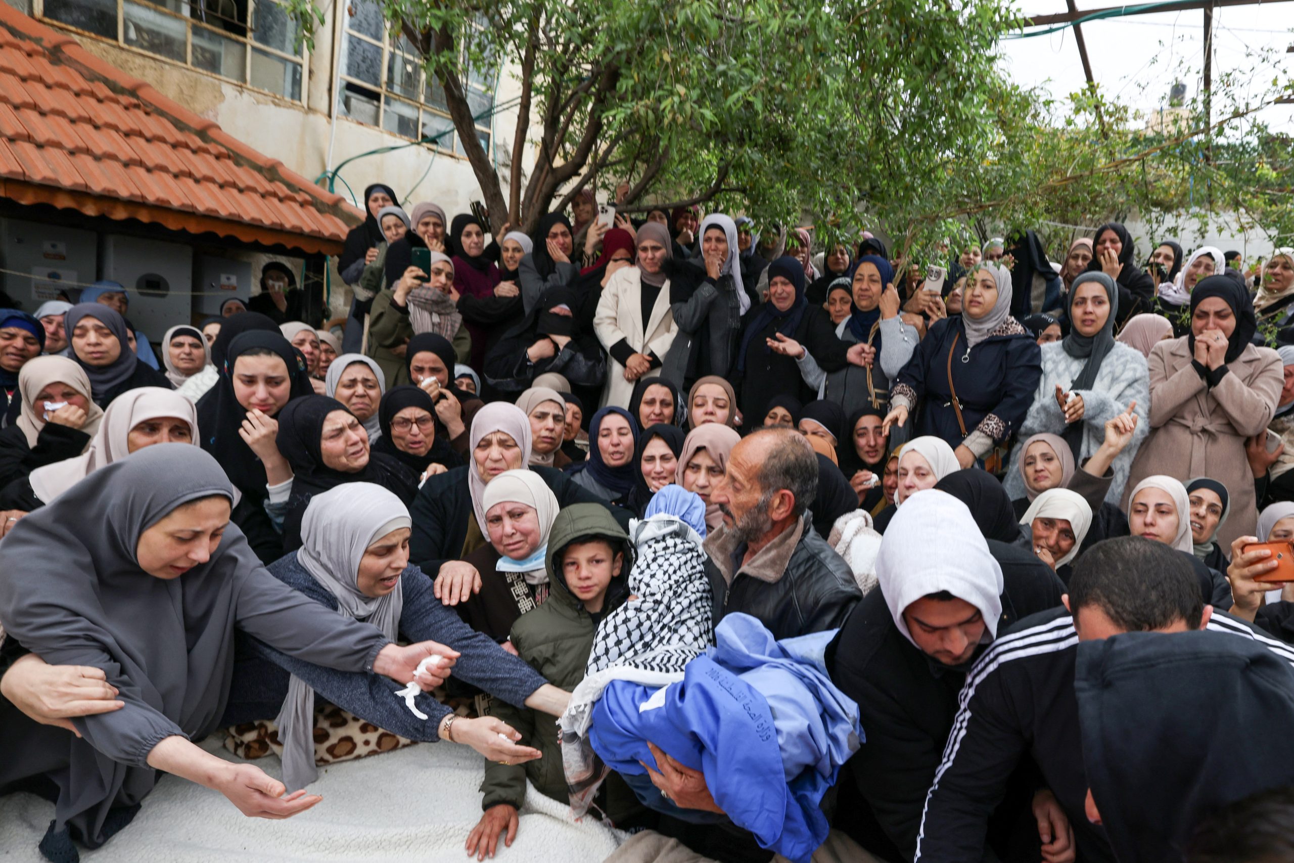Een familielid houdt bij hun begrafenis het lichaam vast van Mohammed Bani Odeh, een van de omgekomen kinderen van het gezin, vast. 15 maart 2026
