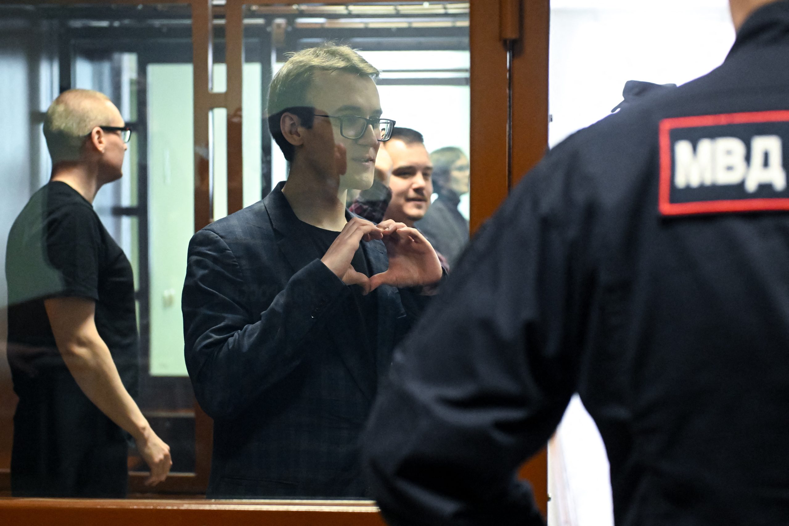 Pavel Sinelnikov, een van de activisten van de pro-democratische jongerenbeweging Vesna die in 2022 als extremistisch en als buitenlandse agent werd bestempeld, beschuldigd van ‘extremisme’ en het verspreiden van ‘valse informatie’ over het Russische leger, gebaart vanuit de beklaagdenbank tijdens de uitspraak in de rechtbank van Sint-Petersburg op 8 april 2026.