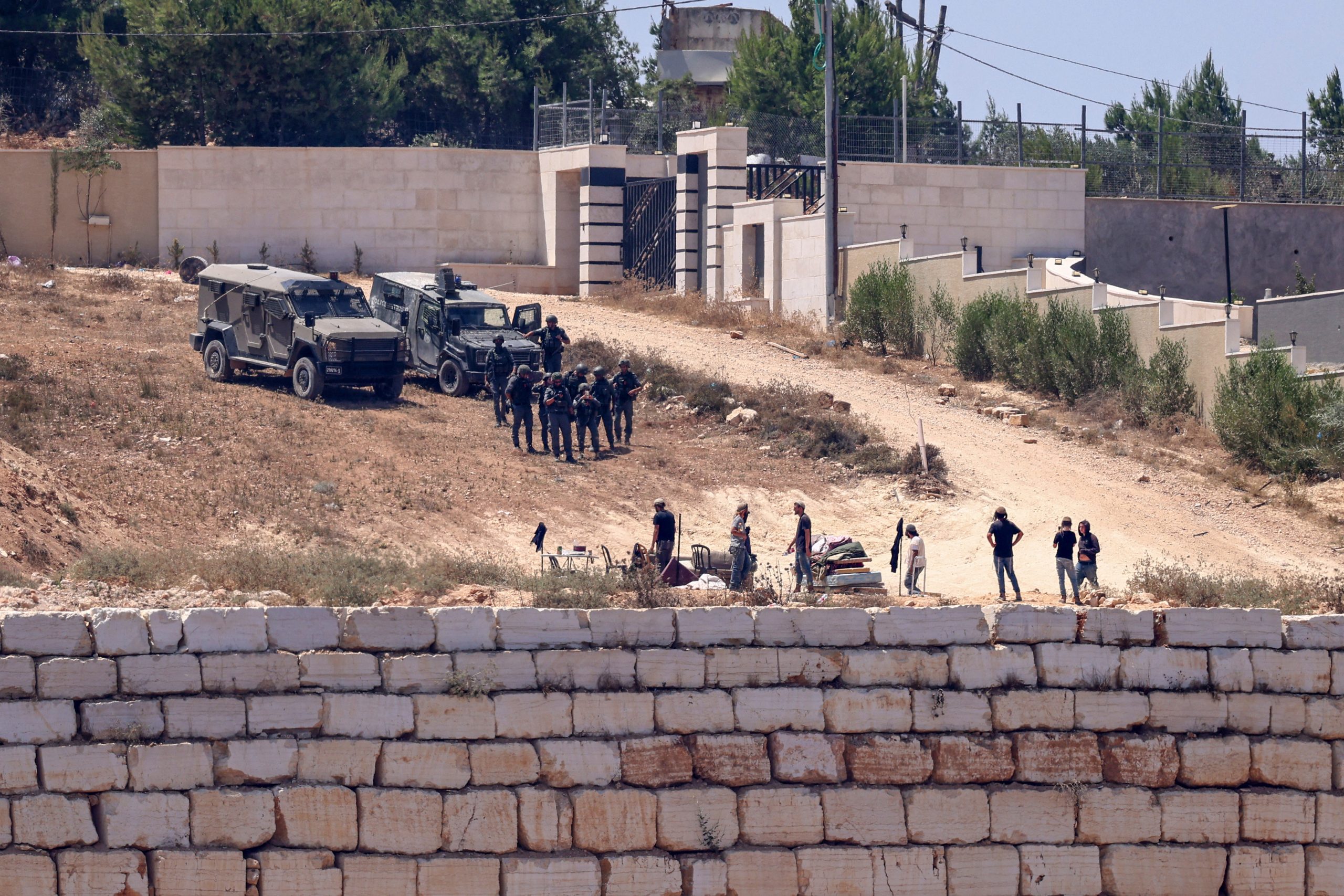 Israelische soldaten staan samen met kolonisten bij de huizen in Qusra. 12 Augustus 2026.